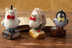 three small figurines are sitting on top of an open book, one is wearing a bow tie and the other has a penguin