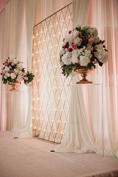 two vases filled with flowers sitting on top of a table next to a wall