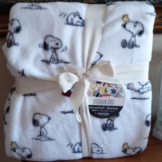 a blanket wrapped in white with snoopy characters on it and a ribbon tied around the edge