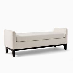 an upholstered white bench with black legs and foot rests on a plain surface