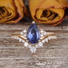 an engagement ring with a blue sapphire surrounded by white and yellow diamonds on a wooden surface