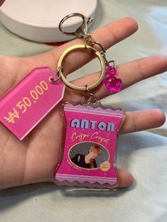 a hand holding a pink keychain with an image on it