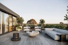 an outdoor living area with couches, tables and plants on the roof top deck