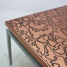 an artistically designed table with metal legs and a pink top that has black lines on it