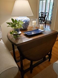 a blue and white vase sitting on top of a wooden table next to a lamp