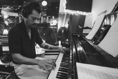 a man sitting at a piano with headphones on and his hands resting on the keyboard