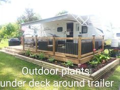 a mobile home sits in the middle of a grassy area with flowers and plants growing on it