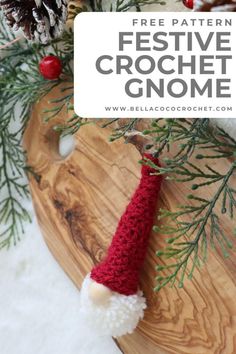 a crocheted gnome hat sitting on top of a wooden board with pine cones