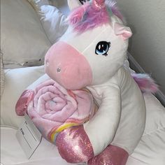 a pink and white stuffed unicorn sitting on top of a bed