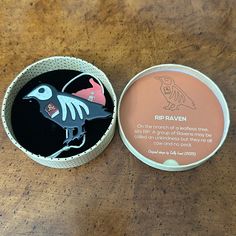 a round box with a bird on it sitting on a wooden table next to a small container