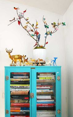 a blue cabinet with two deer figurines on top of it next to a white wall