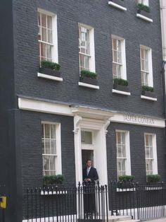 a man standing in front of a black fenced entrance to a building with white windows