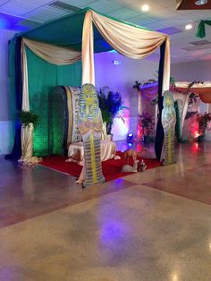 an indoor event decorated with white and blue draping, red carpet, and green curtains