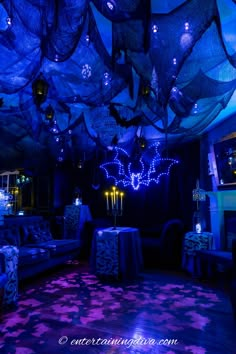 a bat themed party with purple and blue lighting, bats hanging from the ceiling over couches