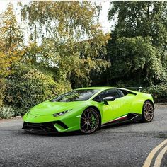 a bright green sports car parked on the side of the road in front of some trees