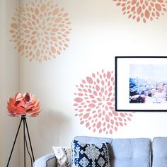 a living room with a gray couch and pink flowers on the wall next to it