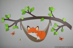 a paper cut out of a fox in a hammock hanging from a tree branch