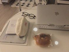 an apple laptop computer sitting on top of a white table next to a bag with a face drawn on it