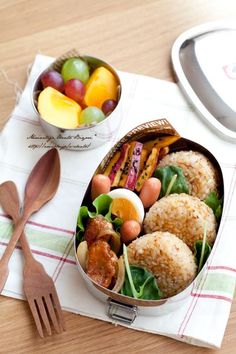 a lunch box filled with meat, vegetables and fruit next to a fork on a napkin