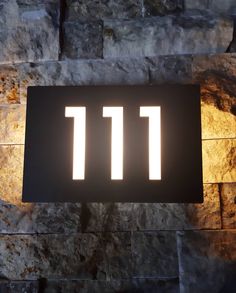 a lit up sign on the side of a stone wall with numbers 11 11 below it