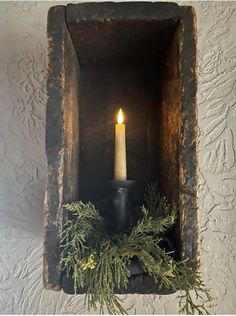 a candle is lit in an old box with greenery on the inside and outside