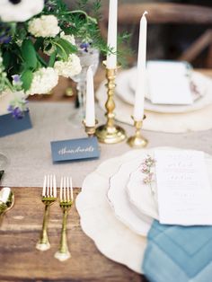 the table is set with white and blue place settings, silverware, and flowers