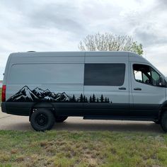 the van is parked on the side of the road with mountains painted on it's sides