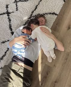 two people laying on the floor hugging each other