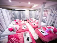 a bed room with several beds covered in pink blankets and pillows on top of each other