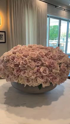 a large vase filled with pink roses sitting on top of a white tablecloth covered table