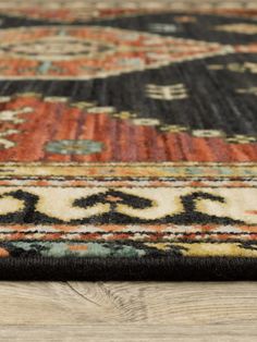 an area rug with various colors and patterns on the wood floor, close - up