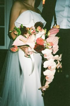 the bride and groom are posing together for a photo with their wedding bouquet in hand