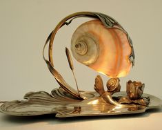 a shell lamp sitting on top of a silver plate with a candle in the middle