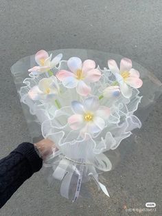 a person holding a bouquet of flowers in their hand on the street with no one around