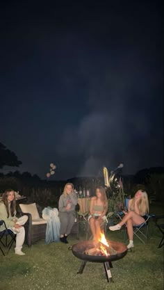 people sitting around a fire pit at night