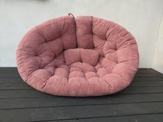 a pink round chair sitting on top of a wooden table next to a white wall