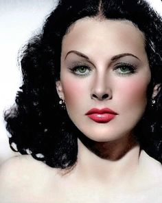 a woman with long black hair and green eyes wearing red lipstick is posing for the camera