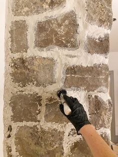 a person in black gloves painting a brick wall