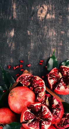 pomegranates on a wooden table with leaves