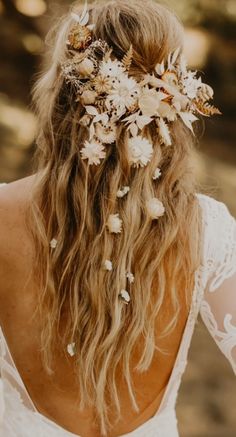 the back of a woman's head with white flowers in her hair and long curly hair