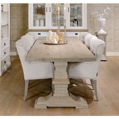 a dining room table with white chairs and a china cabinet in the back wall behind it