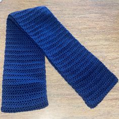 a crocheted blue tie sitting on top of a wooden table