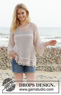 a woman standing on top of a beach next to the ocean with her arms out