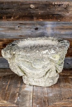 a stone bowl sitting on top of a wooden floor in front of a wood wall