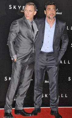 two men in suits standing next to each other on a red carpet at an event