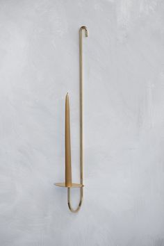 a long wooden handle on the wall next to a metal hook with a toothpick in it