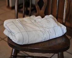 a white blanket sitting on top of a wooden chair next to a tile floor in a kitchen