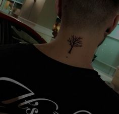 a man with a small tree tattoo on his neck and behind his head is a red car