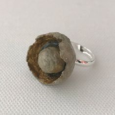 a close up of a ring with a rock in it on a white surface,