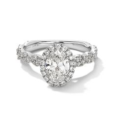 an oval shaped engagement ring with diamonds on the band and side stones in the center